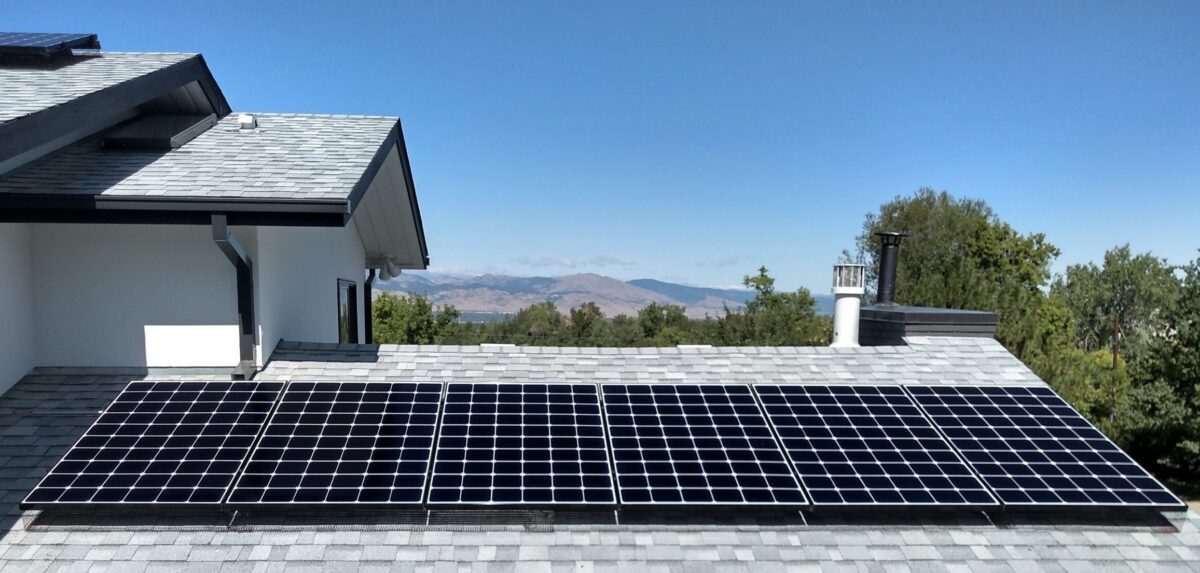 Clean Solar Panels on top of a roof in Colorado with mountains and trees in the background.